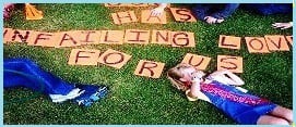 A child laying on the grass with letters that say " has failing for u ".